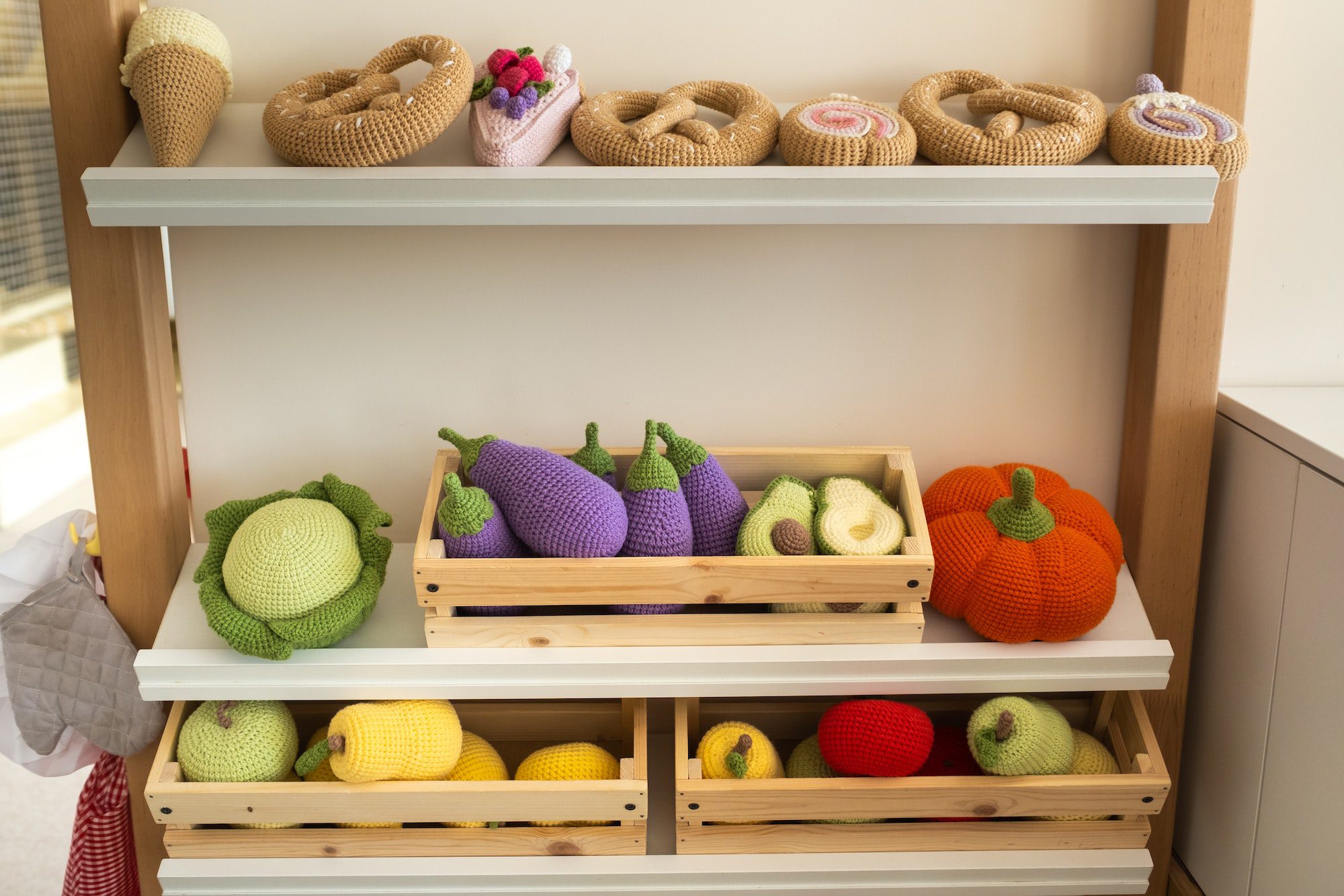 Artificial food in the children's kitchen. On the shelf are vegetables and fruits made of