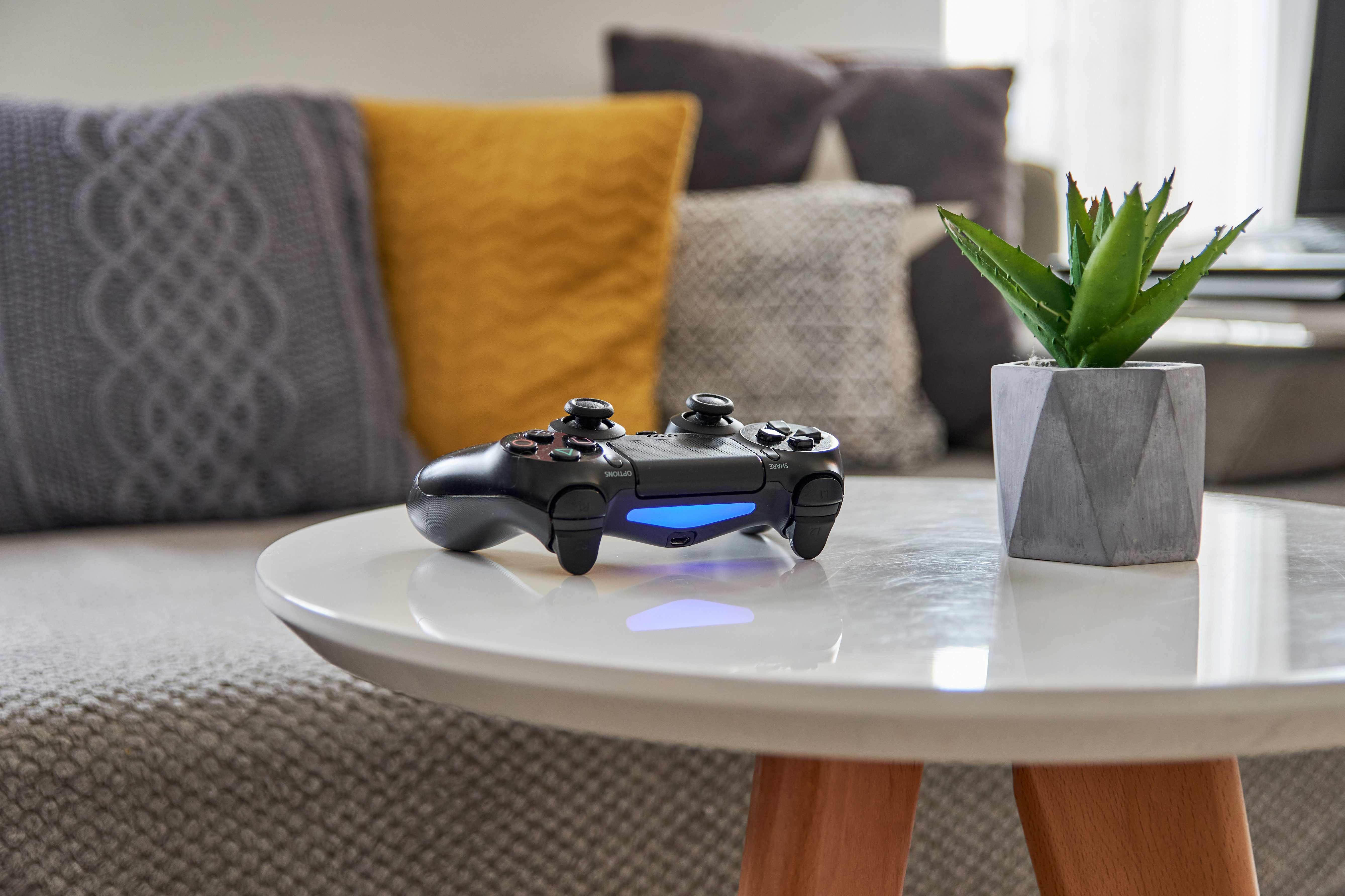 Selective focus, depth of field image of gaming controller on white table in living room.